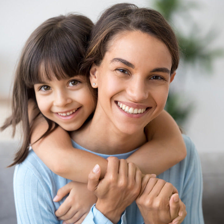 Woman hugging a young girl in a home setting